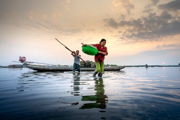 Asian Couple On River Near Boat With Fishing Tools