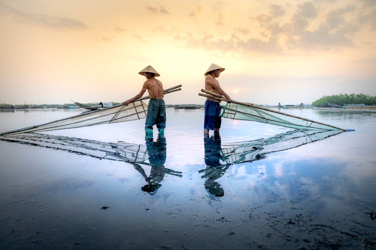 Fishermen In Vietnamese Hats With Fishing Net In River