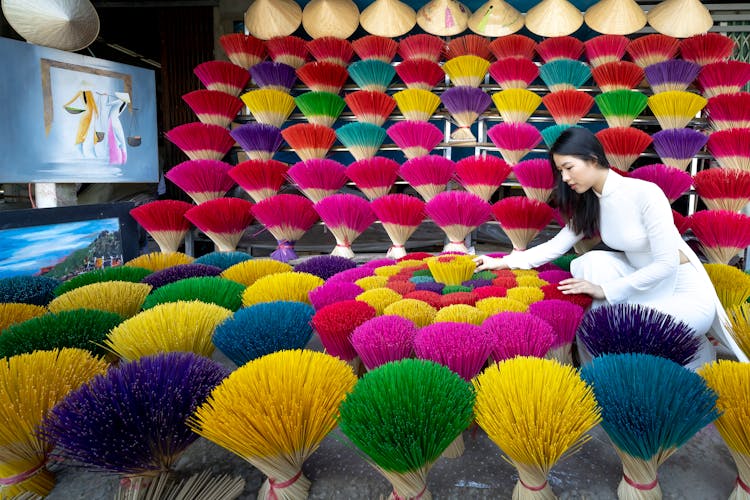 Asian Female Adjusting Colorful Incense Sticks In Market