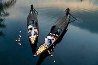 Unrecognizable women with candle lanterns against men in boats