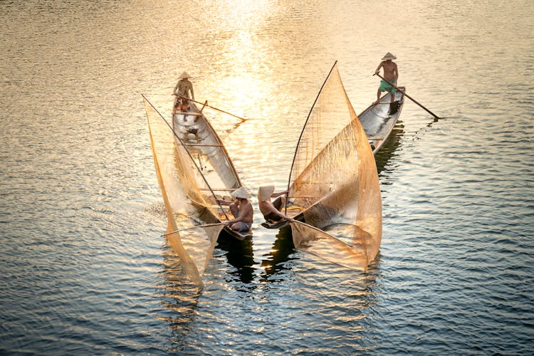 Unrecognizable Fishermen Catching Fish From Boats With Nets In Ocean