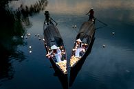 Drone view of anonymous elegant female putting candle lanterns on river water from boats against male partners in evening