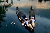 Anonymous women and men in boats on lake in twilight