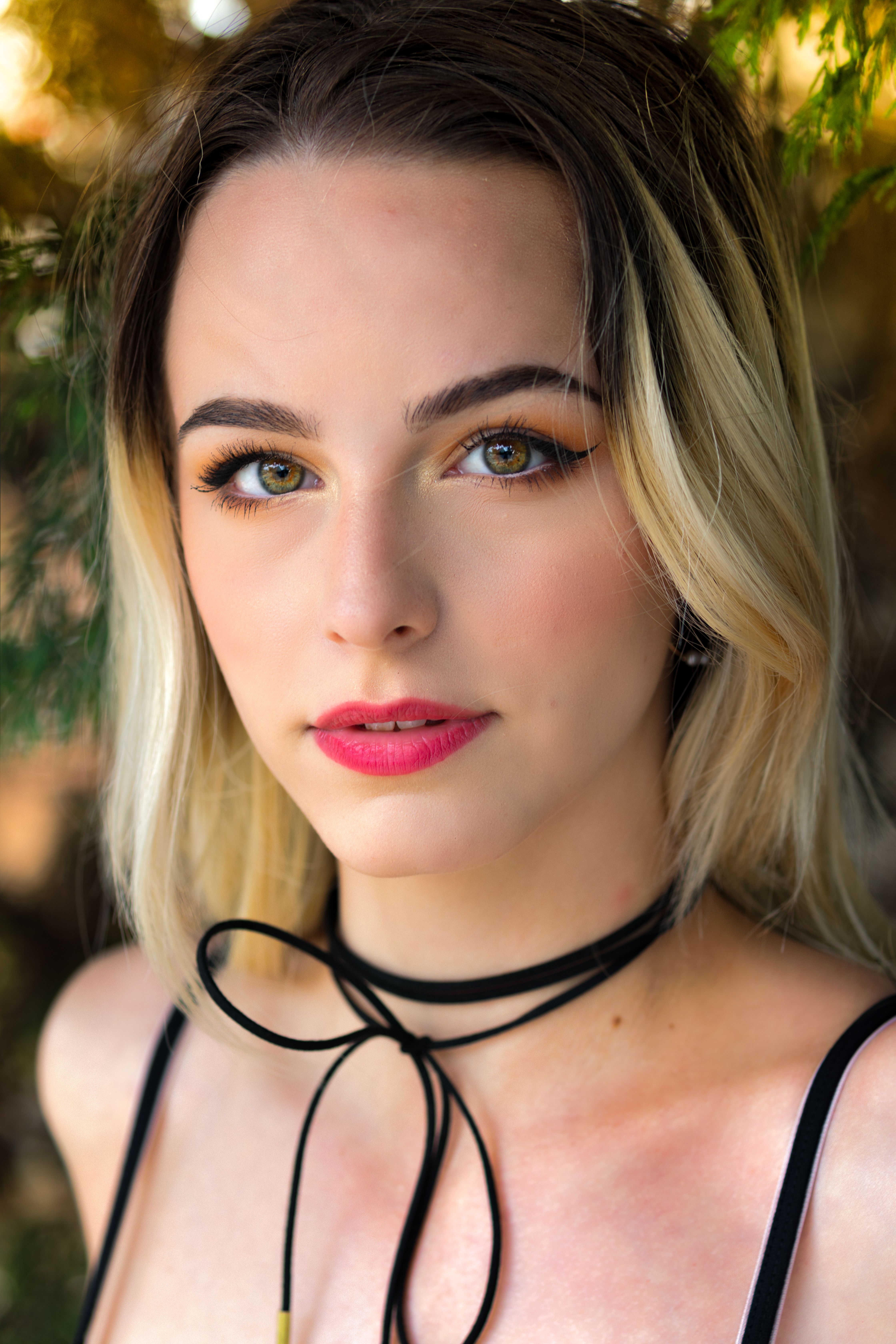 Close-up portrait of a young woman outdoors with natural light and subtle makeup.