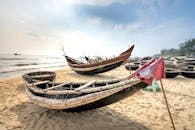 Fishing boats on sandy shore against sea
