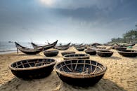 Coracles on sandy beach against ocean in sunlight