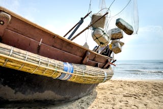 Fishing boat with equipment on ocean shore in sunlight