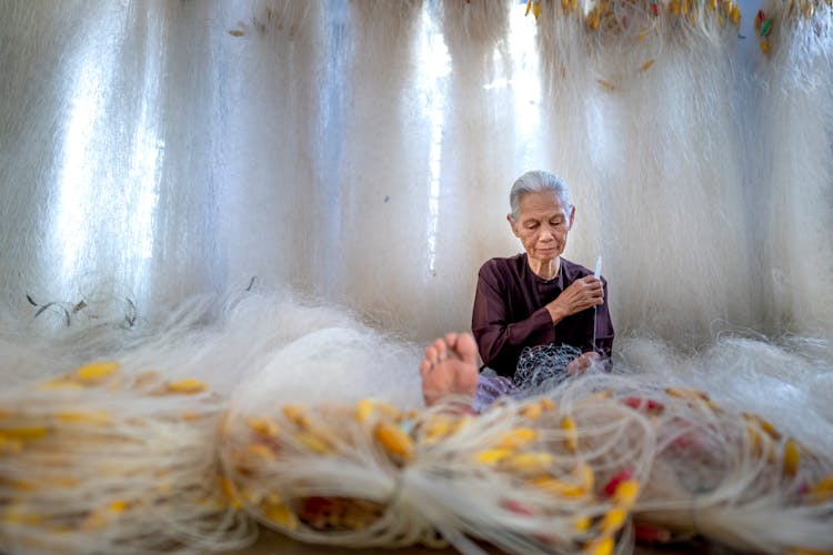 Senior Asian Woman Weaving Fishing Net With Needle