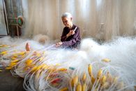 Senior Asian woman making fishing net at home