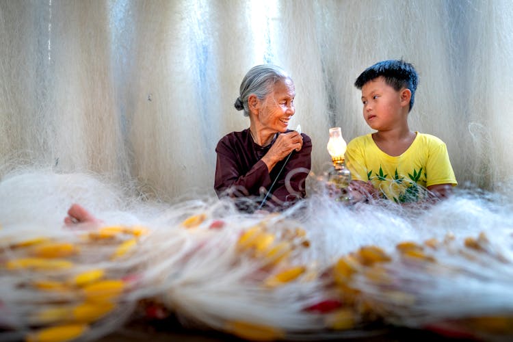 Smiling Asian Grandmother Talking To Grandson Against Fishing Nets