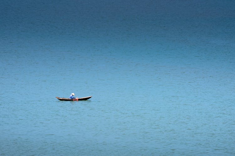 Anonymous Fisherman In Boat On Blue Sea