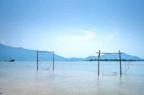 Scenic view of swings between bamboo twigs in rippled lake against mount under blue sky
