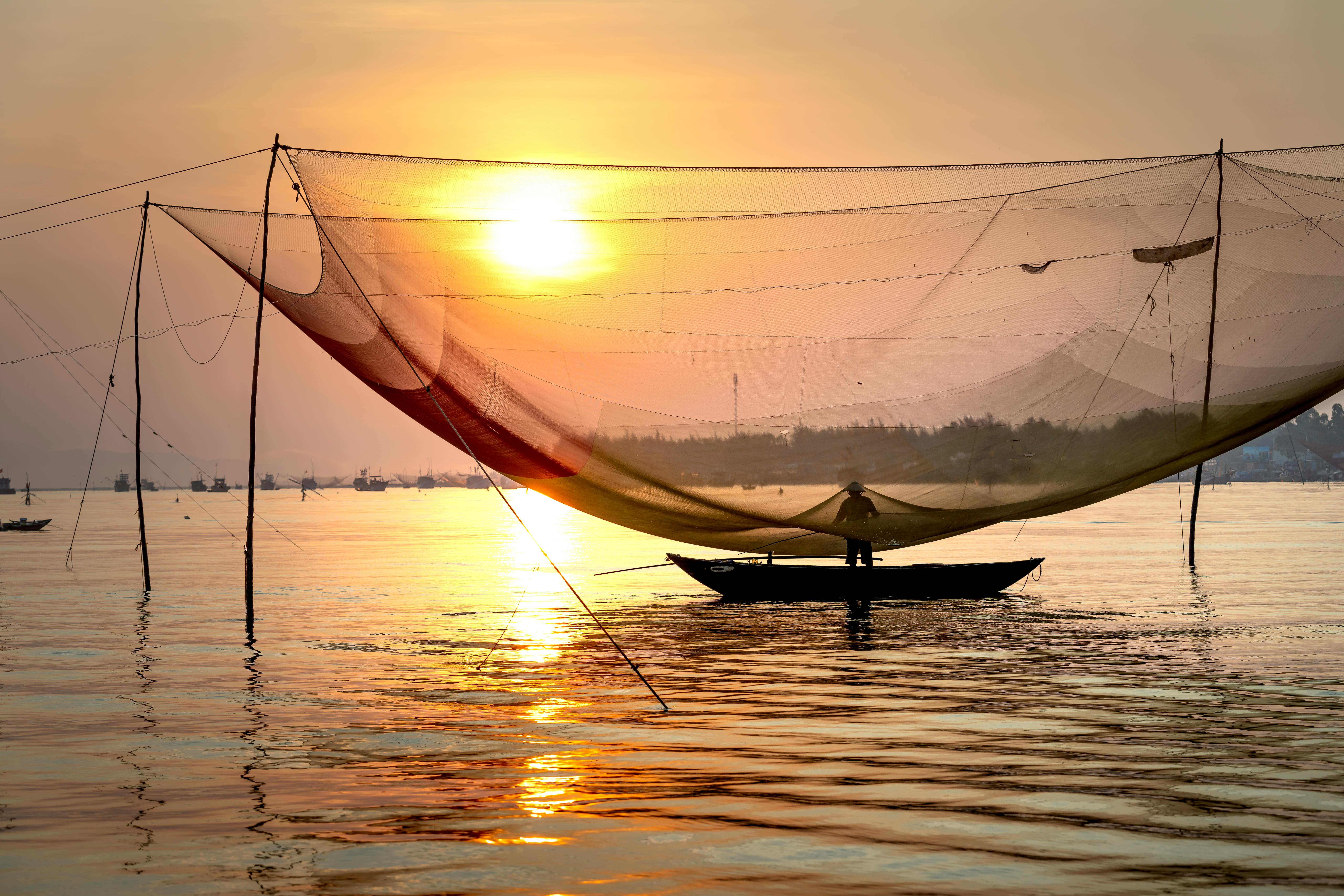 Anonymous fisherman standing in boat under large lift net at sunset · Free  Stock Photo