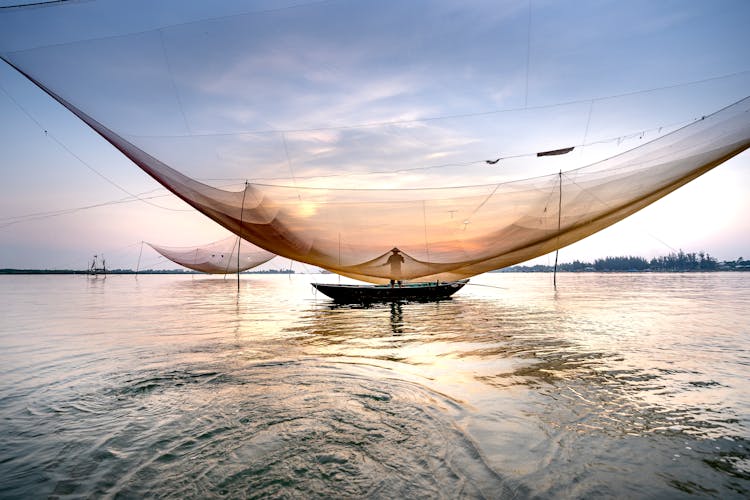 Unrecognizable Man Near Fishing Net On Sea