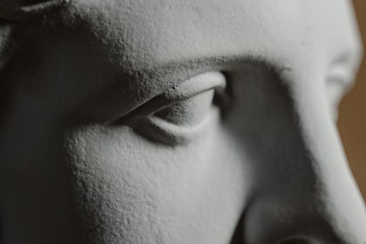 Intricate close-up of a classical sculpture's facial detail highlighting the eye.
