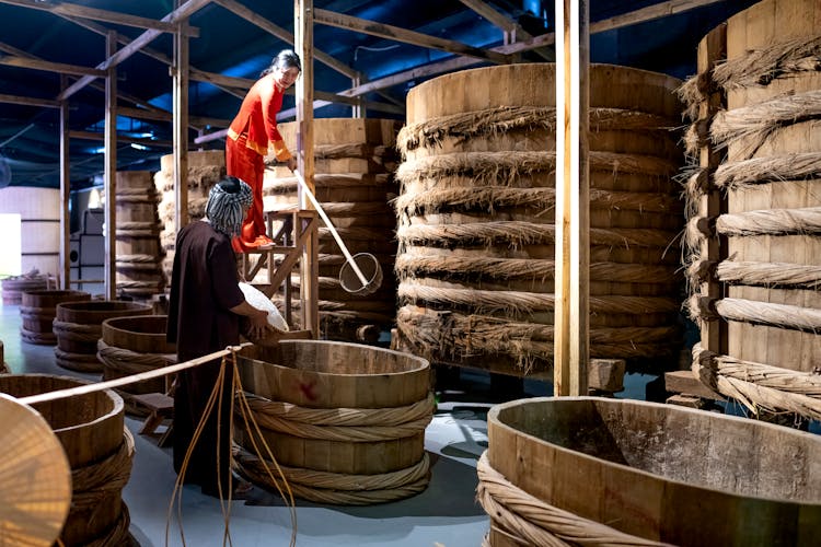 Asian Woman Working With Colleague In Fish Sauce Factory