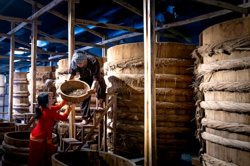 Workers near barrels in fish sauce factory