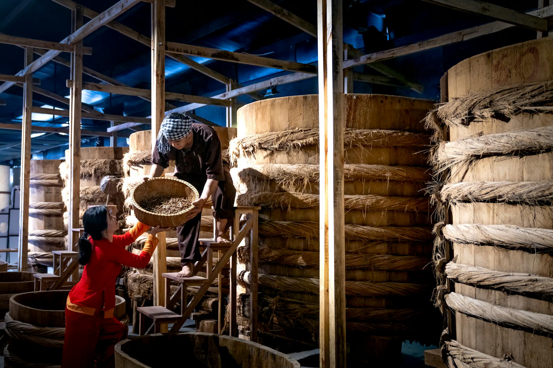 Workers near barrels in fish sauce factory