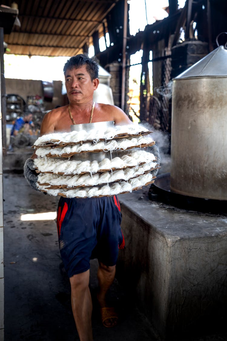 A Man Carrying Winnowing Baskets Of Food