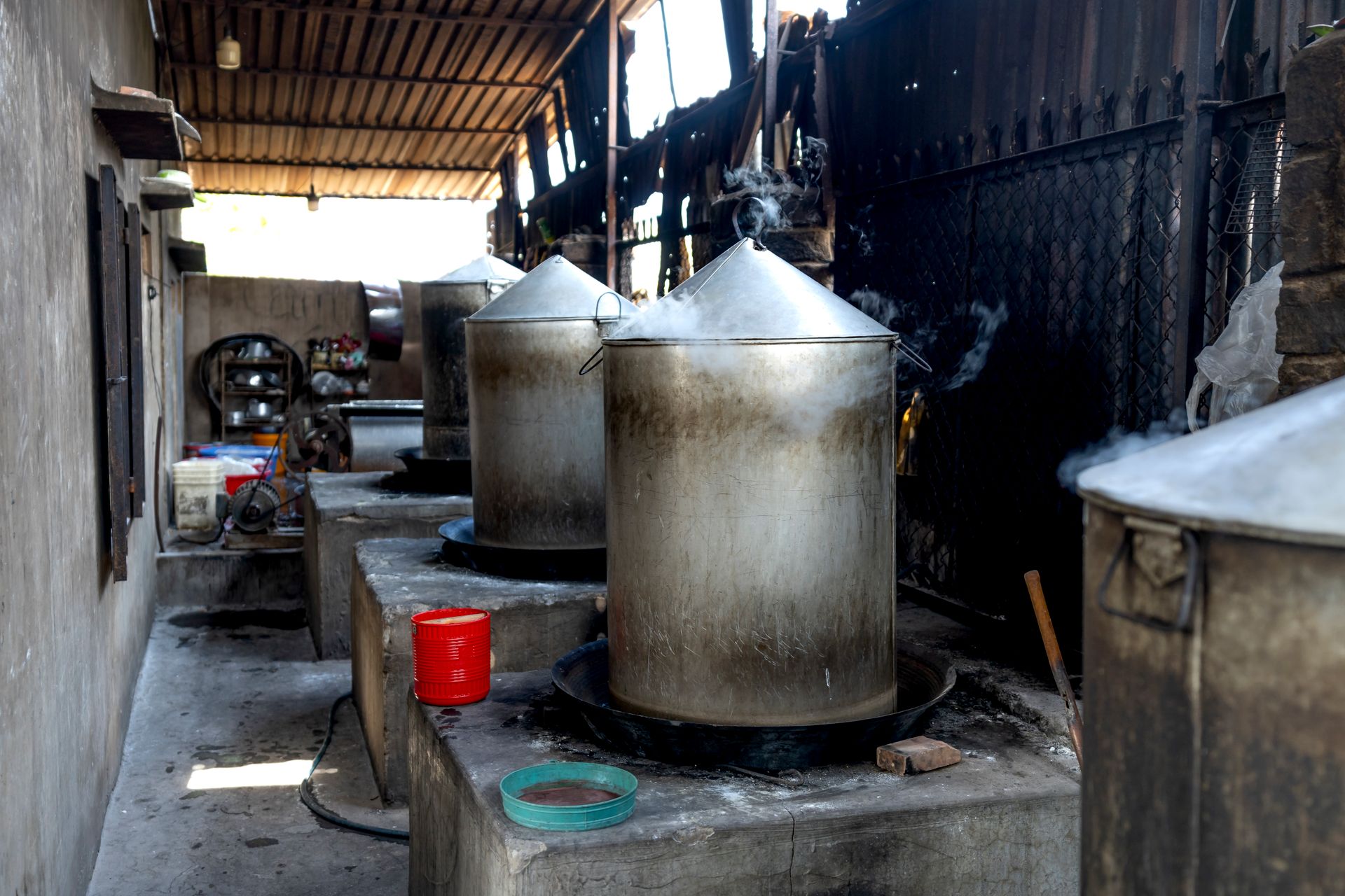 Interior view of a traditional noodle production facility with steaming metal pots.