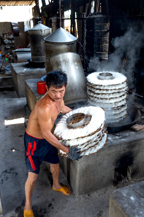 Man making noodle on caps in factory near machines