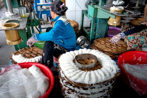Faceless ladies making noodle in factory on machines