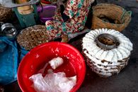 From above of tool for production of traditional Vietnamese noodles with white dough near plastic container and wicker basket