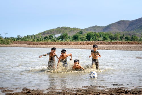 Ethnic kids playing with ball on river