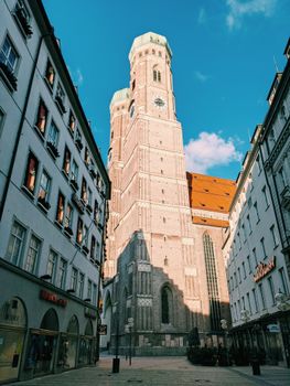 Charming low-angle view of Munich's architecture with a tall tower and blue sky.