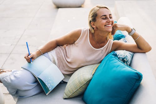 A Woman in a Tank Top Smiling While Sitting on a Couch