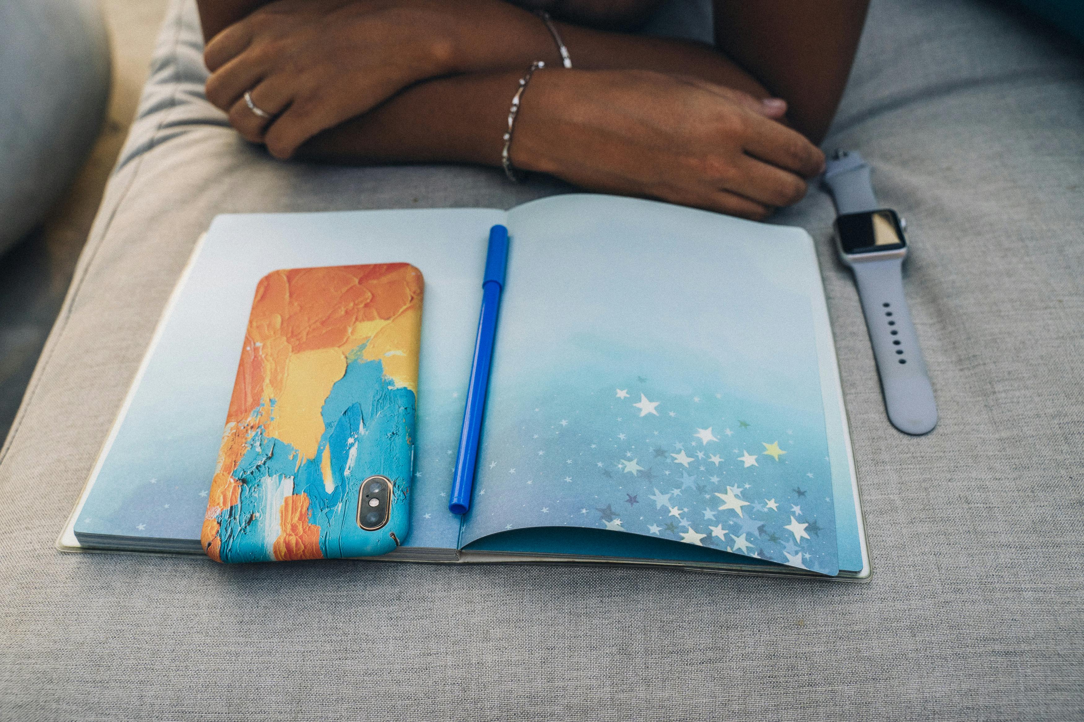 A cozy indoor scene showing a notebook, smartphone, and watch with a person relaxing.