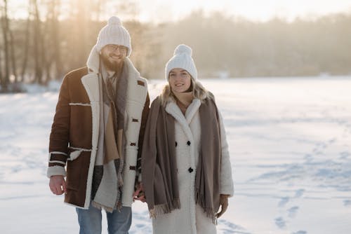 Man and Woman Wearing White Beanies Holding Hands