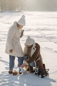 A couple in winter clothing preparing to ice skate on a snowy day outdoors.