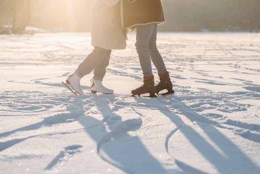 Two people enjoying ice skating on a sunlit snowy surface, capturing the spirit of winter fun.