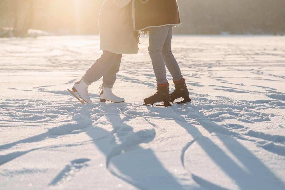 Free Two people enjoying ice skating on a sunlit snowy surface, capturing the spirit of winter fun. Stock Photo