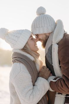 A joyful couple embracing in cozy winter attire, featuring knitted hats and scarves. - Fotografer Sidoarjo