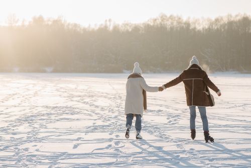 Free A couple skating together on a snowy day, holding hands outdoors, capturing winter romance. Stock Photo
