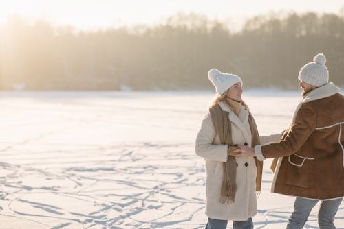 Free Couple holding hands while ice skating on a snowy day, enjoying winter outdoors. Stock Photo