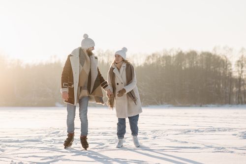 Free A couple holding hands while ice skating on a snowy outdoor landscape during winter. Stock Photo