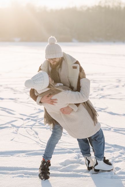 A happy couple ice skating and embracing on a winter day, enjoying the snow and sunshine.