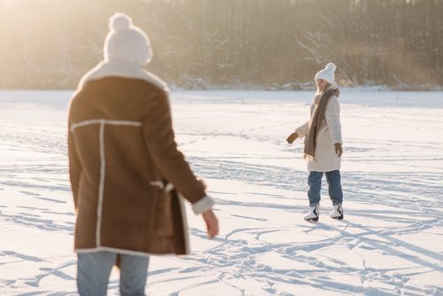 Free A couple enjoys ice skating on a snowy outdoor rink during a bright winter day. Stock Photo