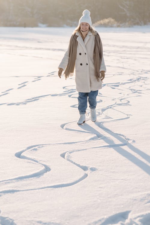 Female in White Coat Standing on a White Snow Covered Ground