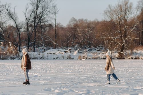 Free Two adults ice skating on a frozen lake in a snowy winter landscape. Stock Photo