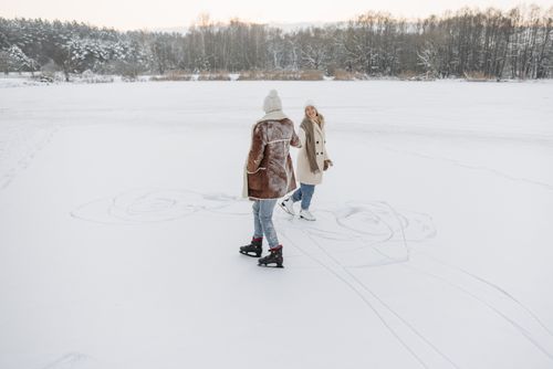 Free A cheerful couple enjoys ice skating on a snow-covered outdoor rink in a picturesque winter setting. Stock Photo