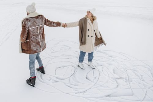 Free A loving couple holding hands while ice skating on a snowy day. Perfect winter fun. Stock Photo