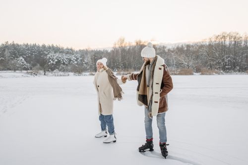 Free Couple holding hands while ice skating on a snow-covered landscape. Stock Photo
