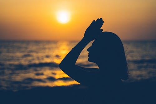 Silhouette of Woman Covering Her Face With Her Hands during Sunset