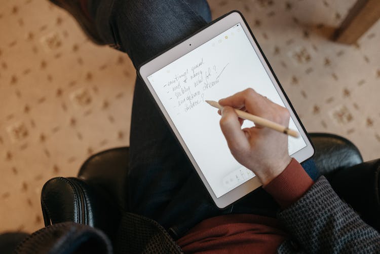 A Person Writing On An Ipad Using An Apple Pencil