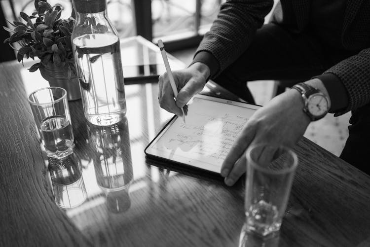 Grayscale Photo Of A Person Writing On An Ipad Using An Apple Pencil