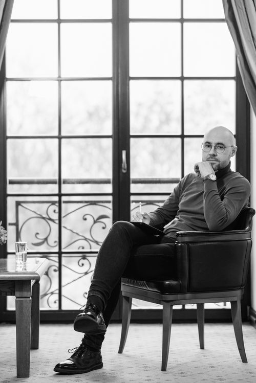 Free Man sitting thoughtfully in chair, holding stylus in modern interior. Stock Photo
